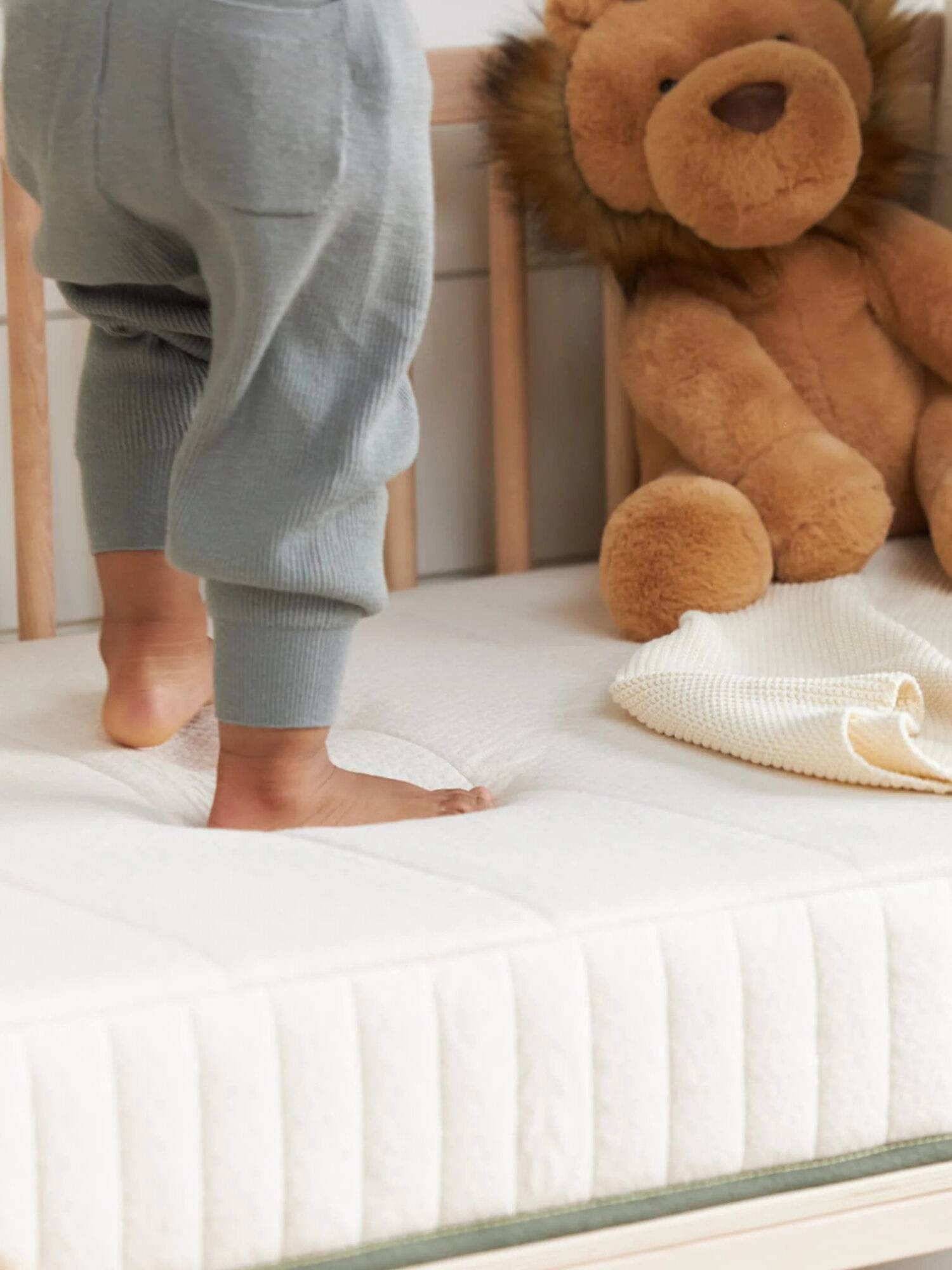 A child's feet stand on a crib mattress