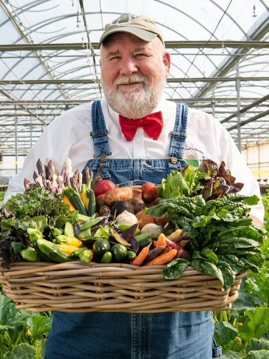 Farmer Jones stands holding a basket of vegetables