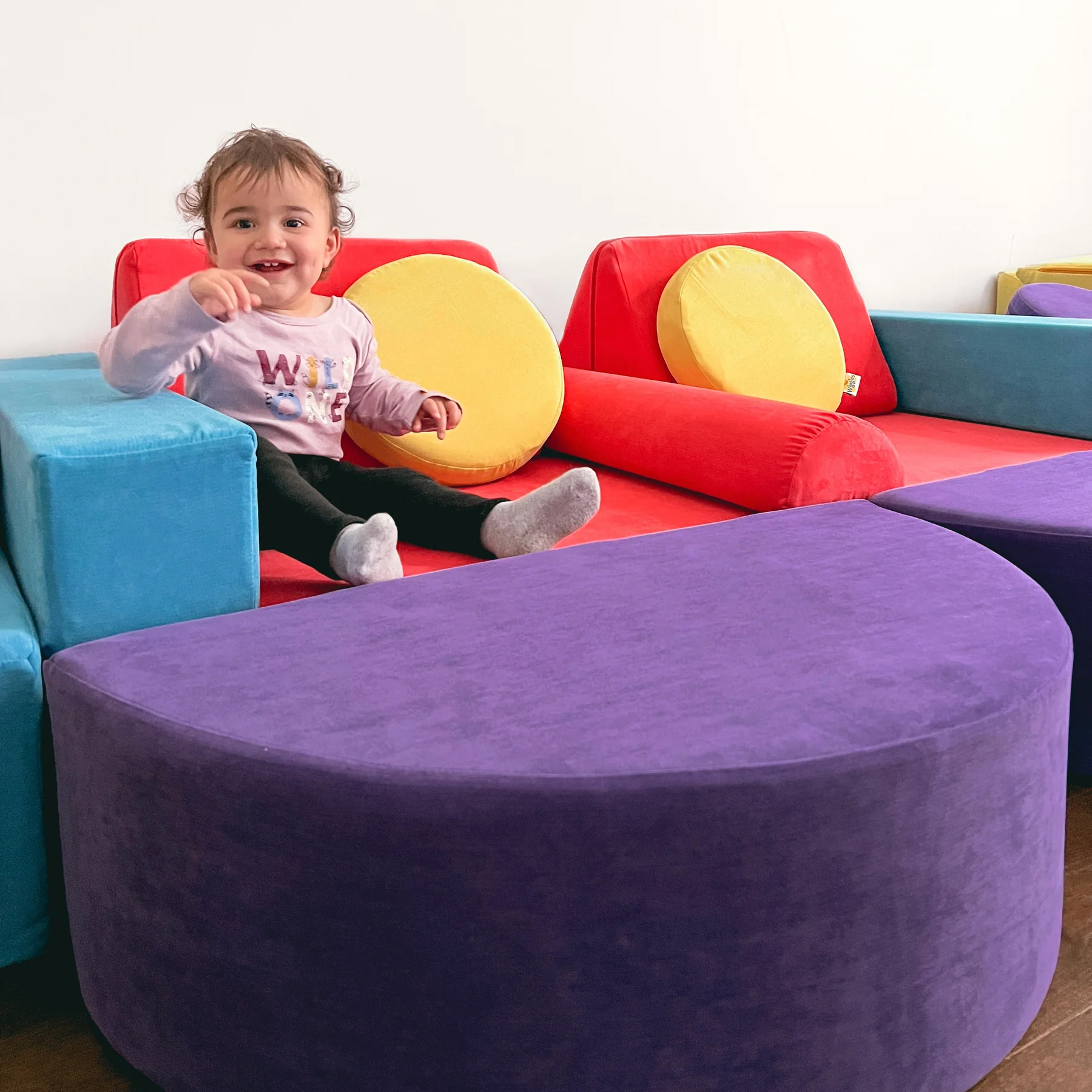 A baby sits in a multi-colored play couch