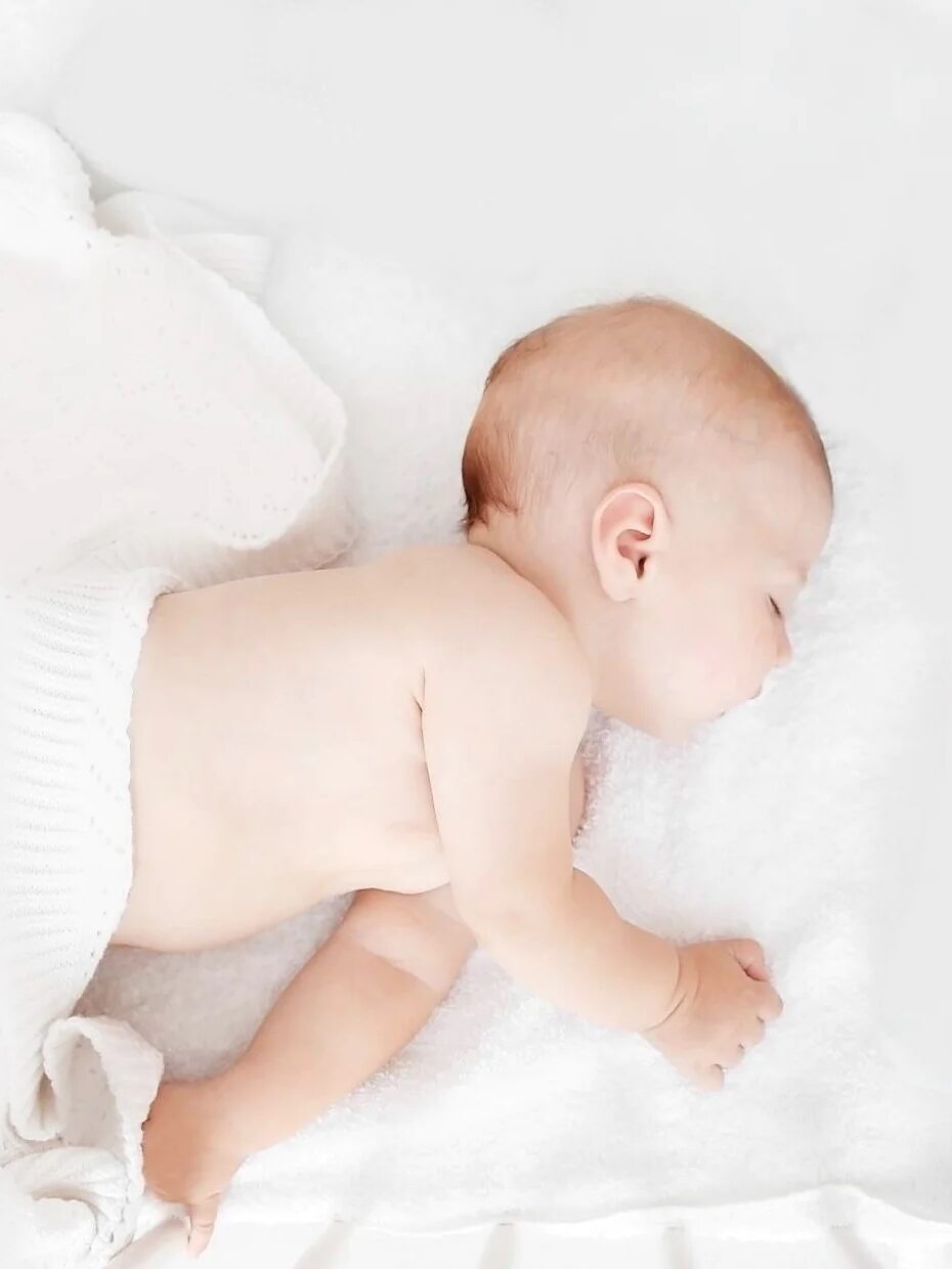 A baby sleeps on a mattress