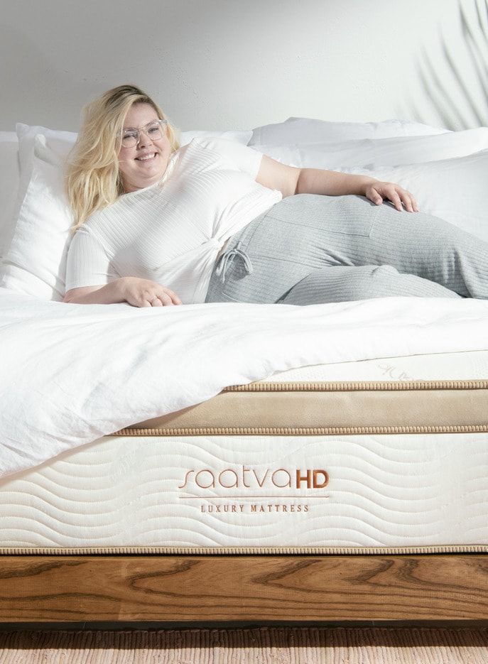 A Saatva HD luxury mattress with a blonde woman laying on top.