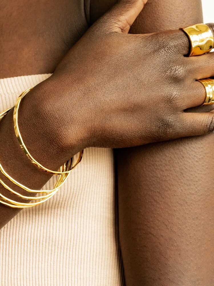 A model's wrist and hand display gold bangles and rings