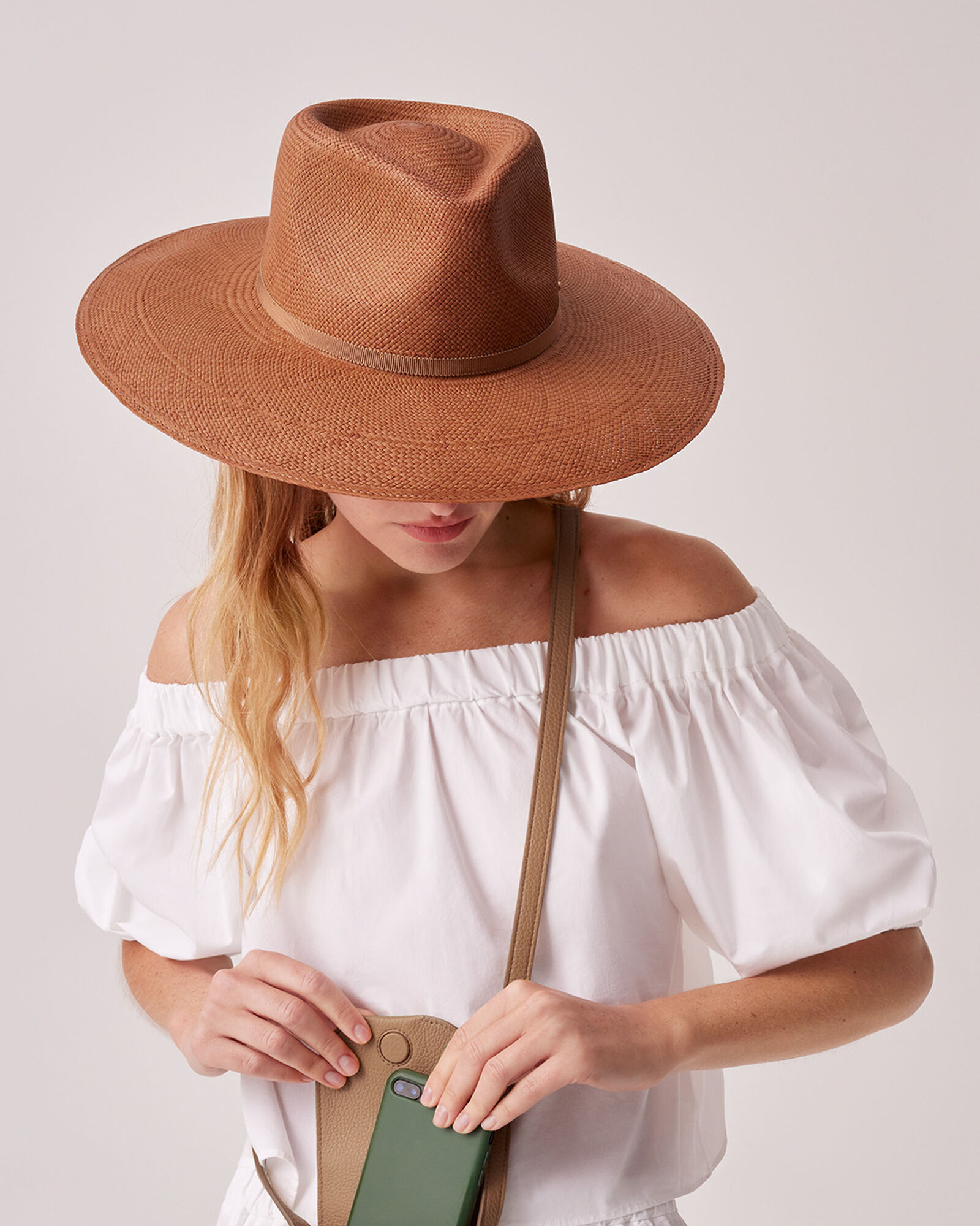 A woman models an orange wide-brimmed straw hat