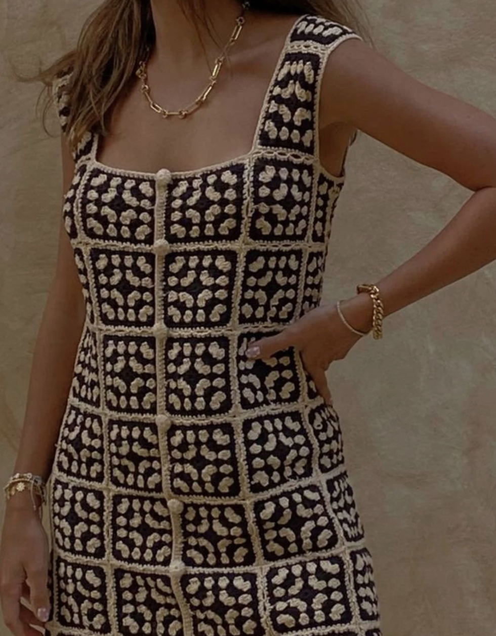A model wears a crochet dress and gold jewelry